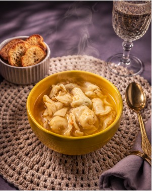 Capelete artesanal servido em caldo quente, com pão torrado ao lado